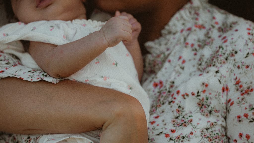 Gros plan d'un bébé tenu dans les bras de sa maman lors d'un shooting naissance en extérieur, CW Photographe Guadeloupe